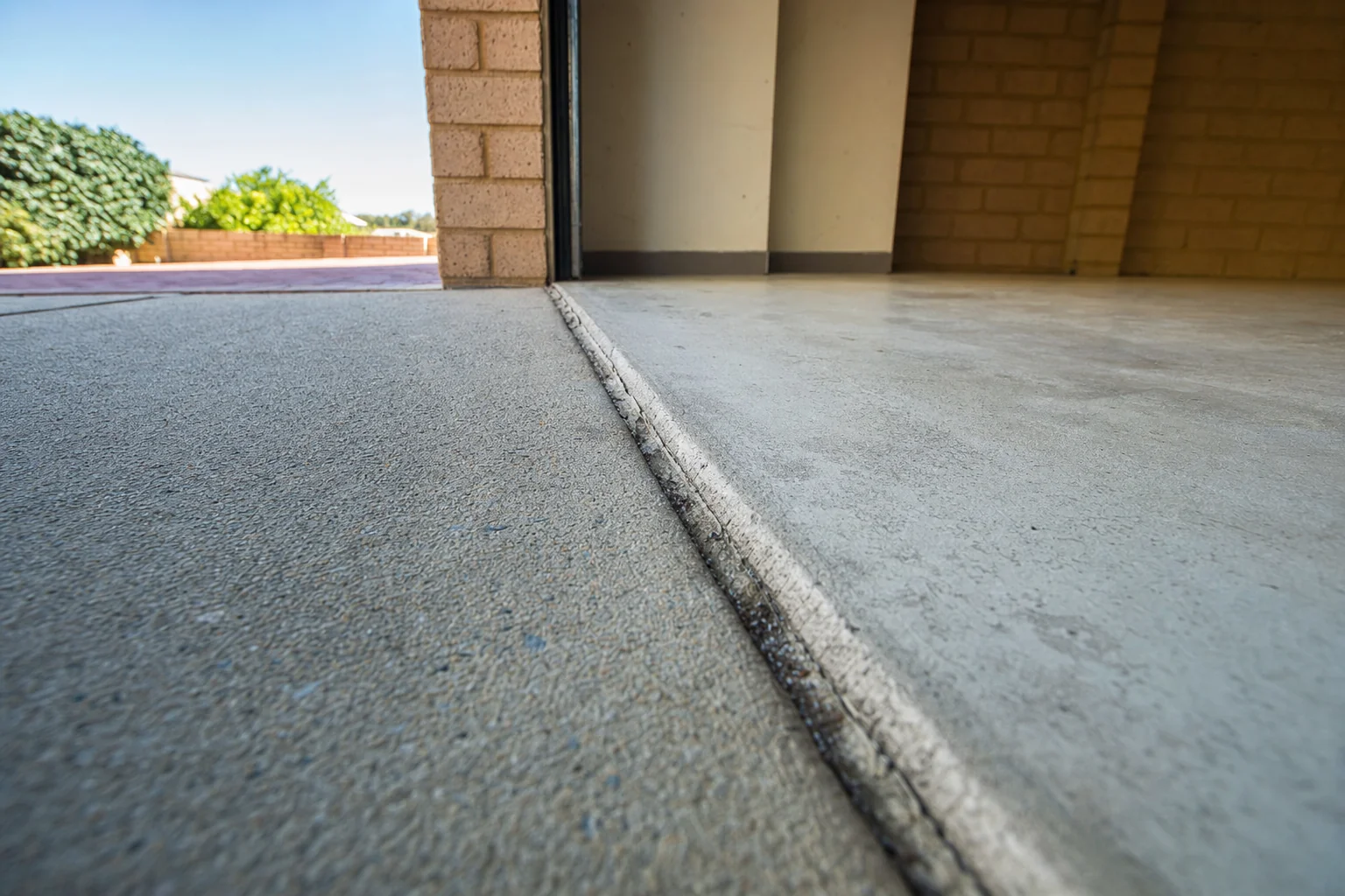 Concrete driveway sitting slightly below the garage slab at an Australian home, with the joint between them opened up.