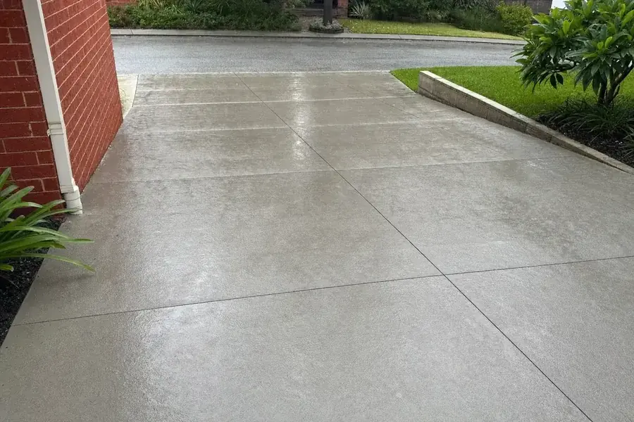 Plain grey concrete driveway graded for drainage away from a Perth home