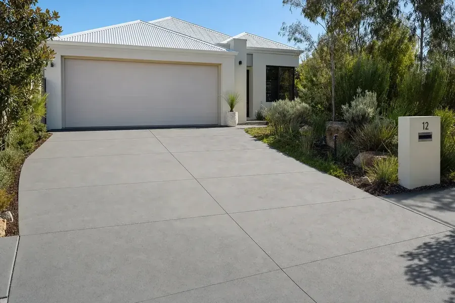 Plain grey concrete driveway in front of a rendered Perth home with a double garage